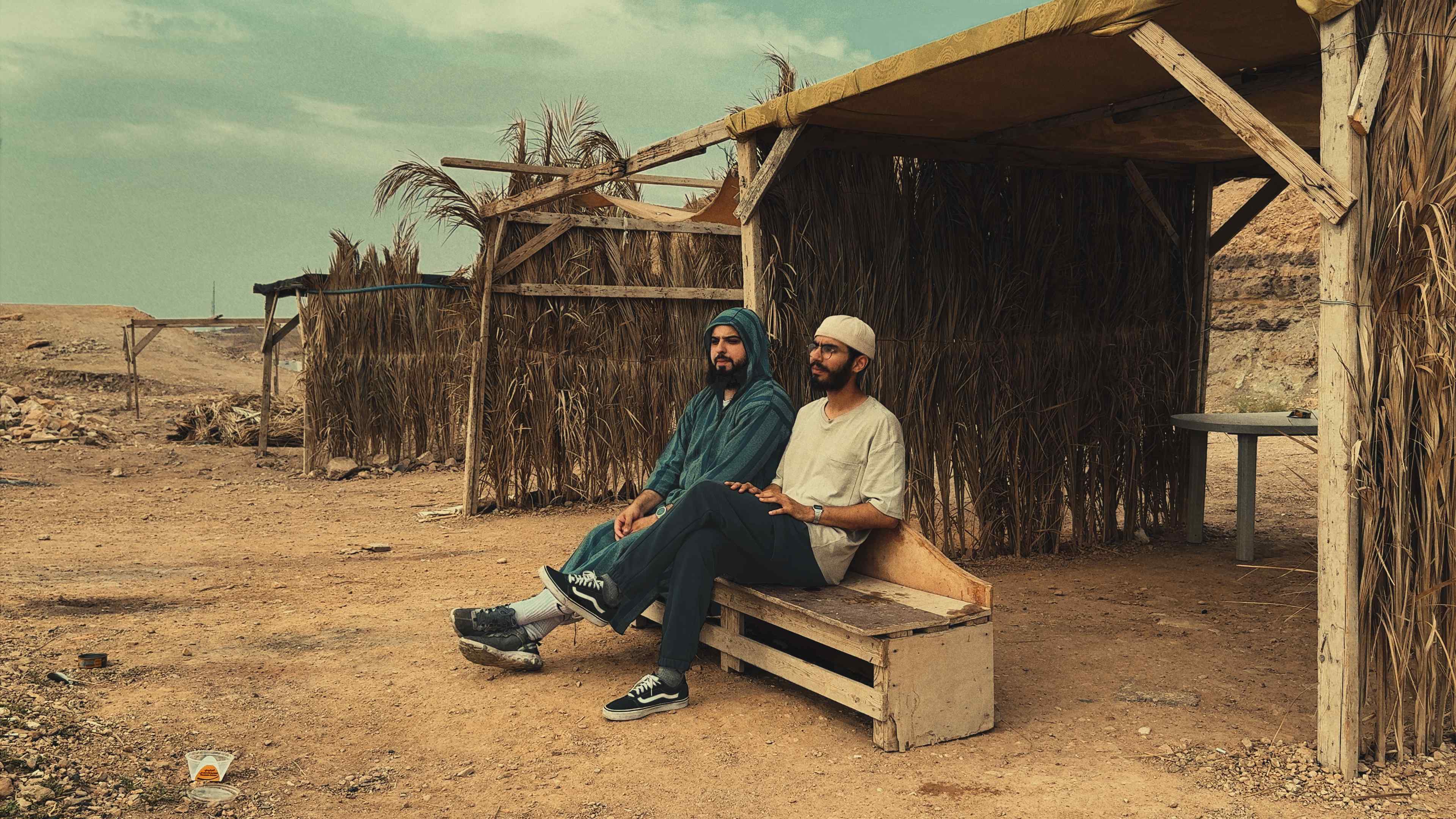 Resting by a palm-frond shelter in the desert