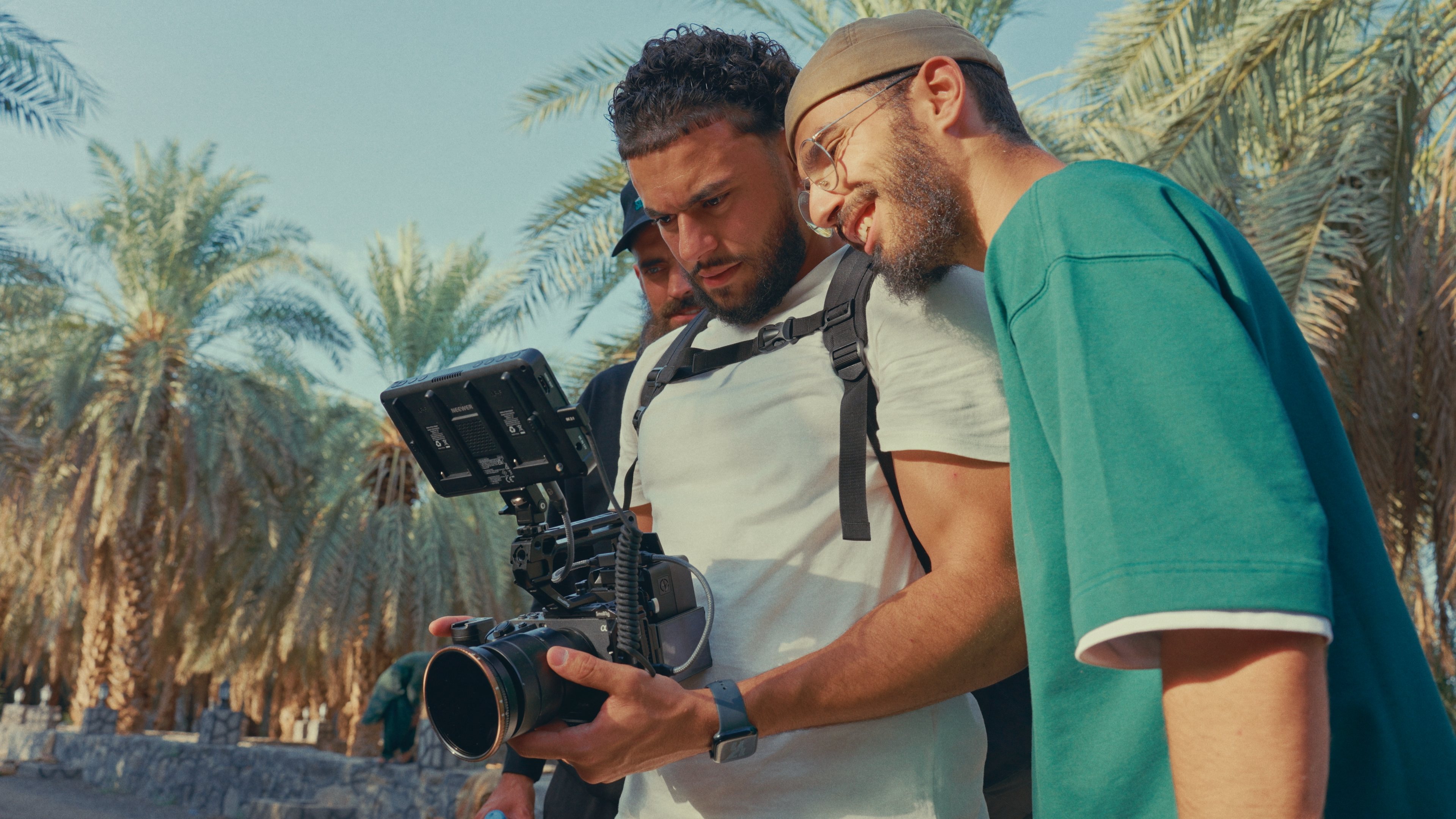 The Sacred Chronicles crew reviewing footage on a cinema camera among the palm groves